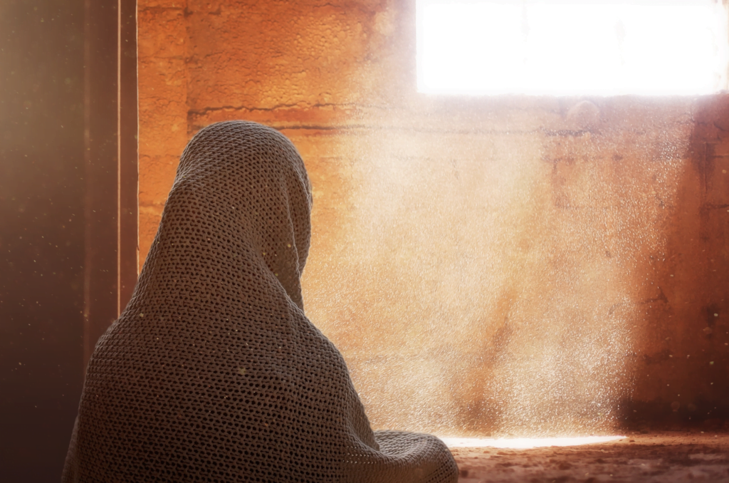 femme voilée de dos dans une maison traditionnelle